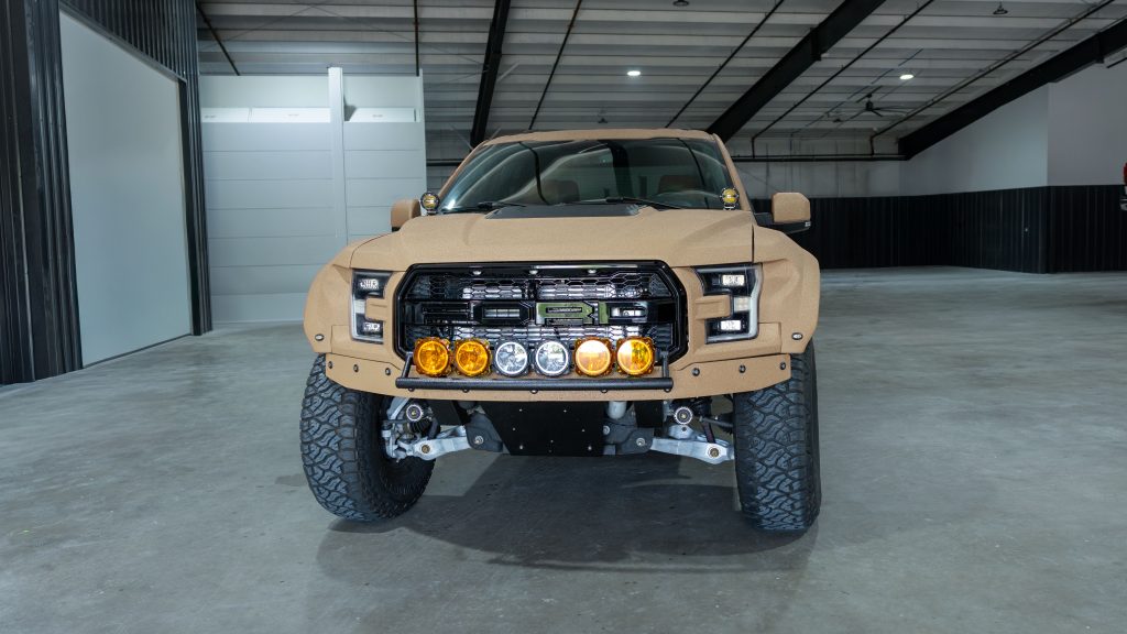 Custom Ford truck featuring armored exterior finish, off-road bumper, integrated auxiliary lighting, lifted suspension, and all-terrain tires installed by Apex Custom Innovations
