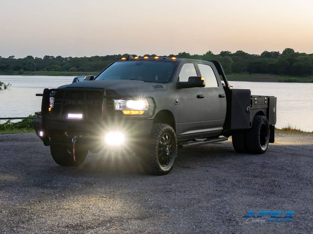 2022 Ram 3500 flatbed truck with Apex Armor coating, Ranch Hand bumper, Rigid light bars, and Warn winch at sunset
