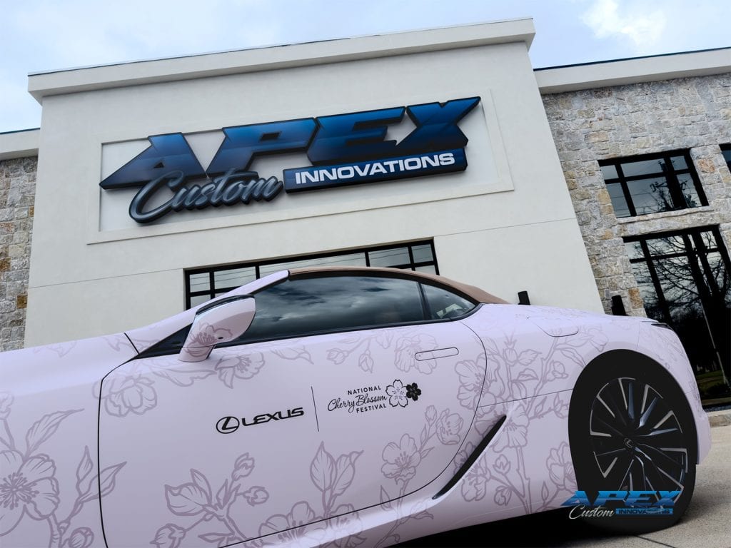 Close side view of Lexus LC500 with Lexus and National Cherry Blossom Festival logos on pale pink floral wrap